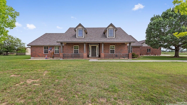 view of front of house with a porch, brick siding, a shingled roof, and a front lawn