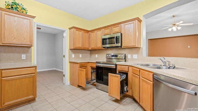 kitchen featuring light tile patterned flooring, light countertops, a sink, appliances with stainless steel finishes, and backsplash
