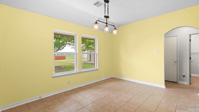 spare room featuring visible vents, arched walkways, baseboards, and light tile patterned flooring