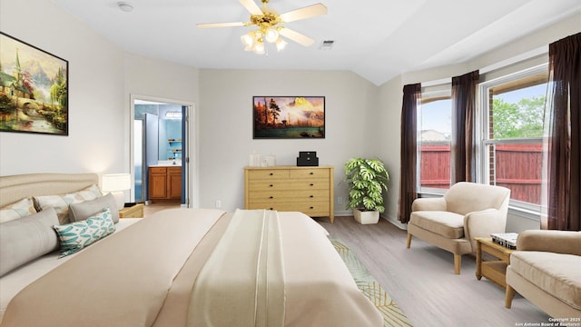bedroom with visible vents, vaulted ceiling, light wood-type flooring, baseboards, and connected bathroom