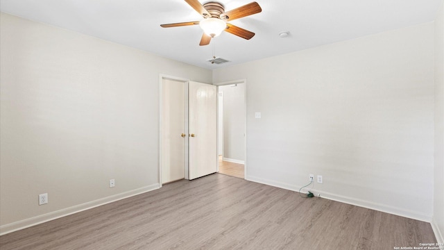 spare room featuring a ceiling fan, baseboards, visible vents, and wood finished floors
