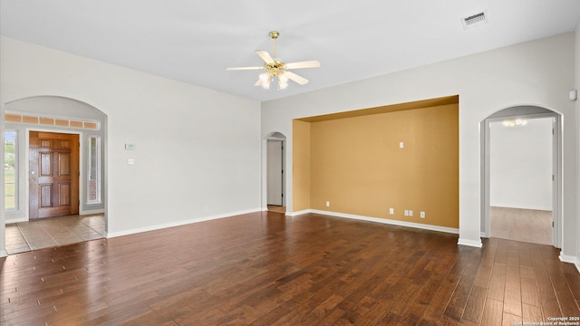 unfurnished room featuring a ceiling fan, visible vents, arched walkways, baseboards, and hardwood / wood-style floors