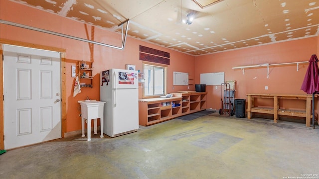 garage featuring a workshop area and freestanding refrigerator