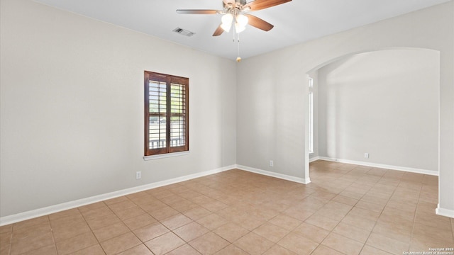 unfurnished room with ceiling fan, arched walkways, baseboards, light tile patterned floors, and visible vents