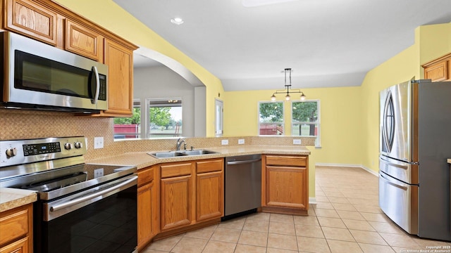 kitchen with plenty of natural light, appliances with stainless steel finishes, tasteful backsplash, brown cabinets, and a sink