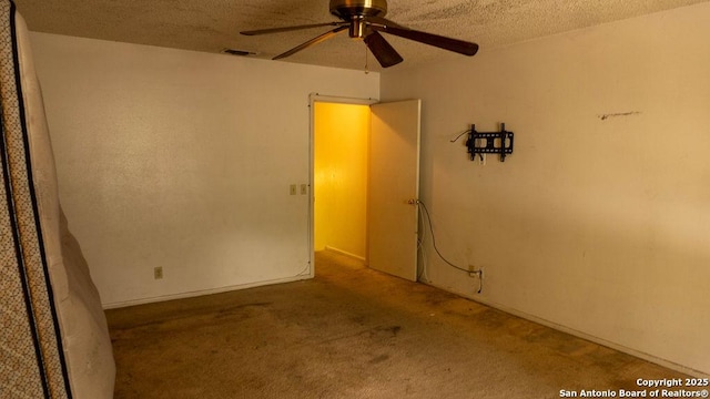carpeted spare room featuring ceiling fan, a textured ceiling, and visible vents
