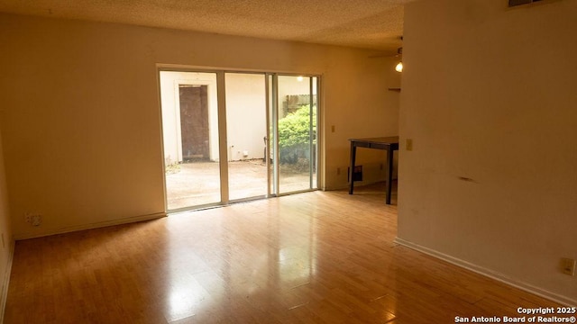 spare room with ceiling fan, a textured ceiling, baseboards, and wood finished floors
