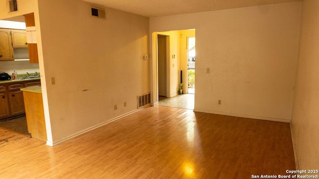 empty room featuring visible vents and light wood-type flooring