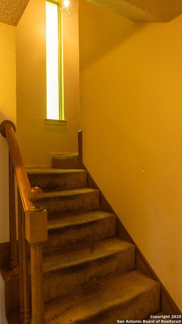 stairway featuring a textured ceiling