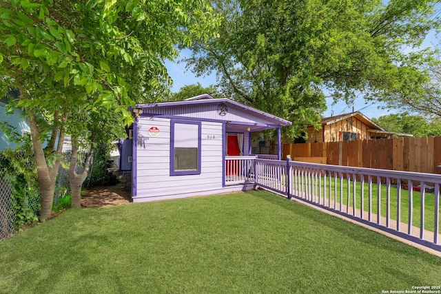 view of front of house featuring an outbuilding, a fenced backyard, and a front yard