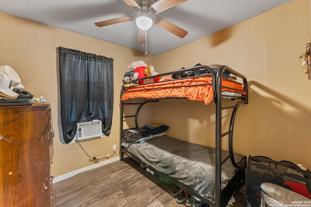 bedroom with baseboards, cooling unit, a ceiling fan, and wood finished floors