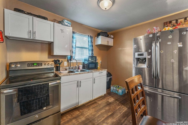 kitchen with a sink, white cabinets, dark wood-style floors, and stainless steel appliances
