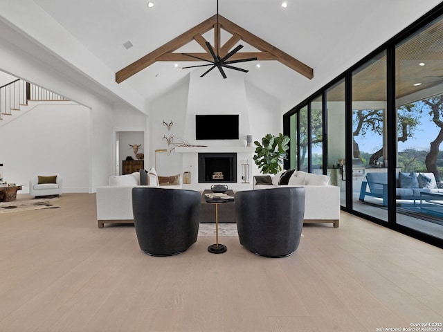living area with beam ceiling, a fireplace, light wood-style floors, high vaulted ceiling, and stairway