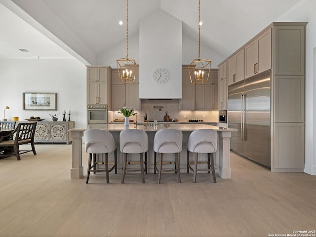 kitchen with light countertops, a notable chandelier, appliances with stainless steel finishes, and high vaulted ceiling