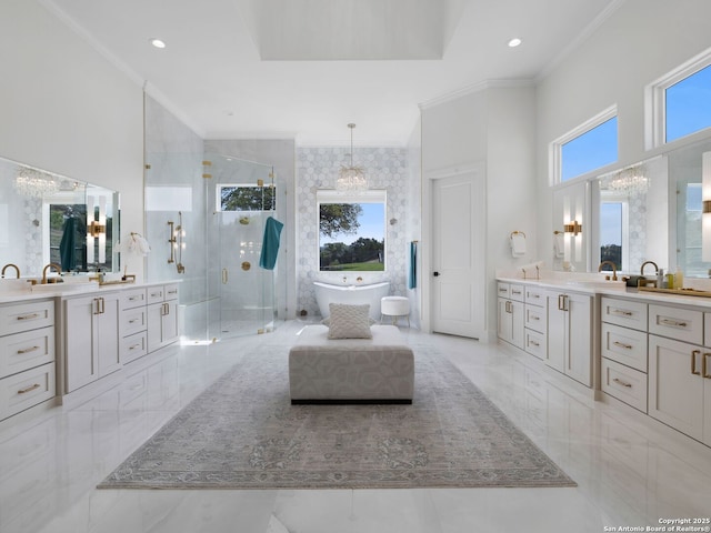 full bath with a freestanding bath, a stall shower, two vanities, marble finish floor, and ornamental molding