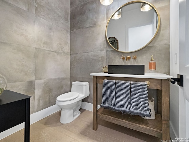 half bath featuring vanity, toilet, and tile walls