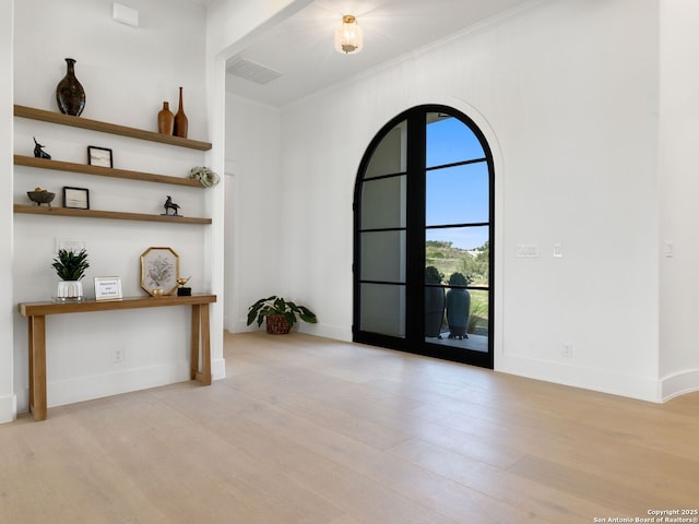 interior space with visible vents, ornamental molding, baseboards, and wood finished floors