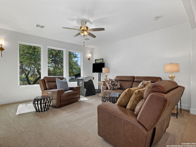 living room with visible vents, baseboards, ceiling fan, and light colored carpet