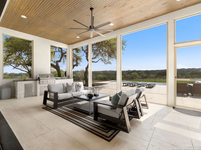 view of patio featuring grilling area, exterior kitchen, ceiling fan, and an outdoor living space