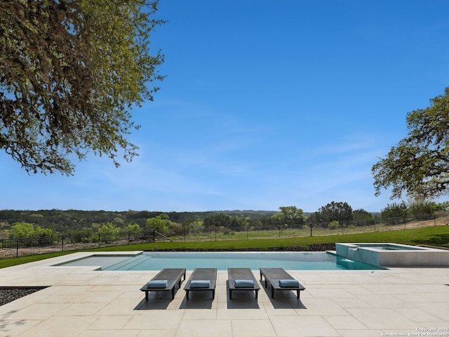 view of swimming pool with a patio, a pool with connected hot tub, and fence