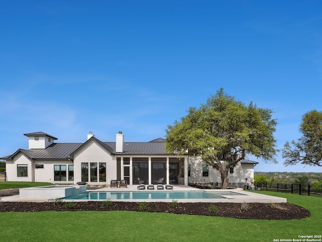 rear view of house featuring a lawn, fence, a chimney, and a standing seam roof