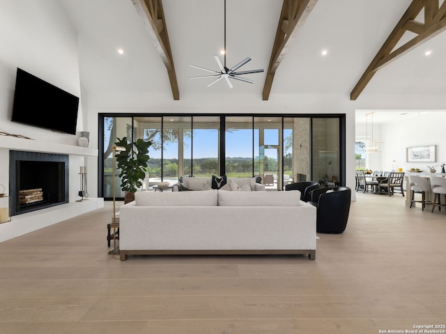 living area featuring plenty of natural light, a fireplace with raised hearth, high vaulted ceiling, and beamed ceiling