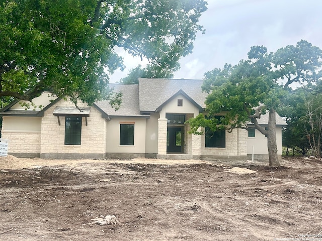 view of front of house featuring a shingled roof and stone siding