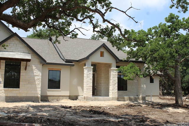 property under construction with a shingled roof and stone siding