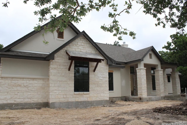 view of front of property with a chimney, roof with shingles, stucco siding, and stone siding