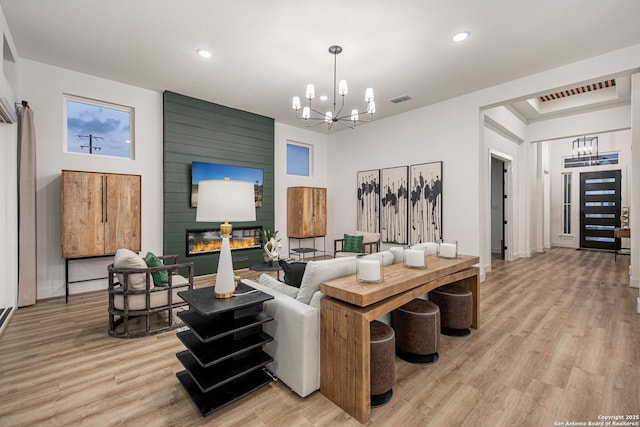 living room with recessed lighting, light wood finished floors, and a notable chandelier