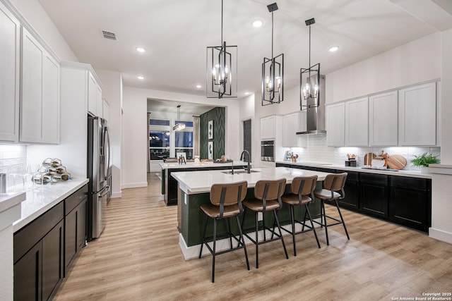kitchen featuring light countertops, stainless steel appliances, visible vents, and an island with sink