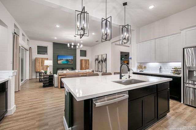 kitchen featuring appliances with stainless steel finishes, an inviting chandelier, a sink, an island with sink, and open floor plan