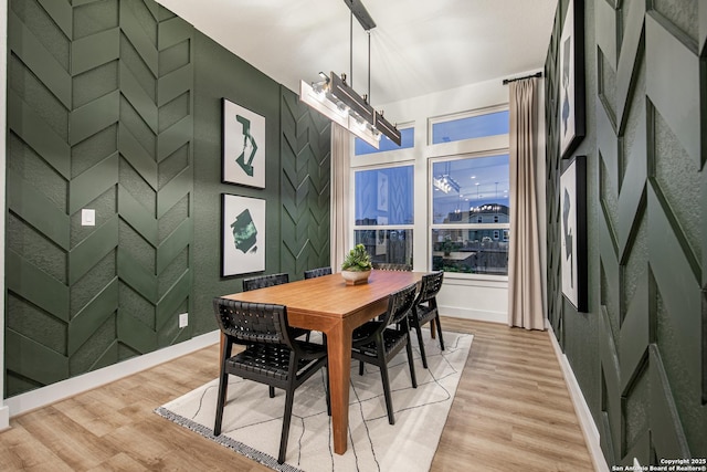 dining space with an inviting chandelier, baseboards, and light wood-style flooring
