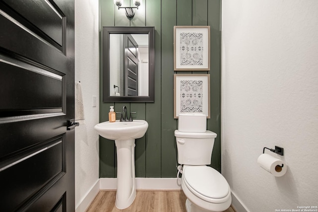 bathroom with baseboards, wood finished floors, and toilet
