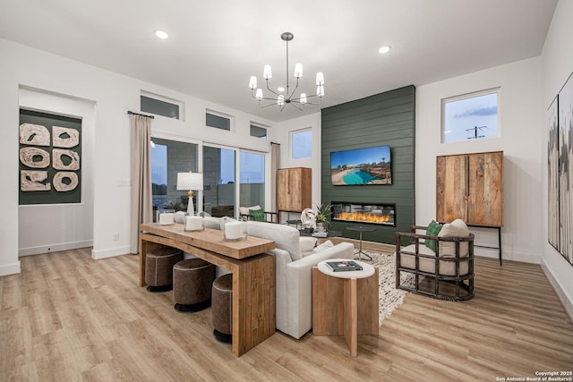 living area with an inviting chandelier, recessed lighting, light wood-style floors, and baseboards