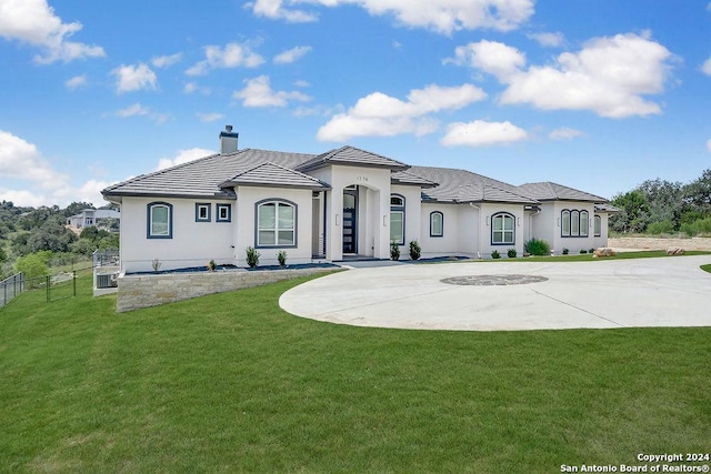 view of front of house with a front lawn, fence, curved driveway, stucco siding, and a chimney