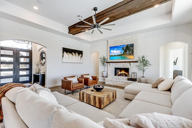 living room featuring arched walkways, ceiling fan, a fireplace, and visible vents