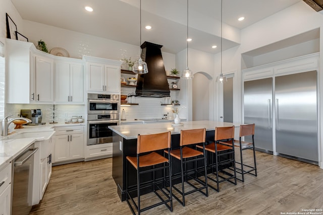 kitchen with open shelves, a sink, stainless steel appliances, white cabinetry, and island range hood