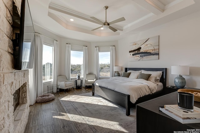 bedroom featuring crown molding, beam ceiling, a fireplace, recessed lighting, and wood finished floors