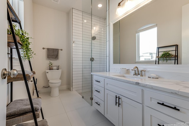bathroom featuring vanity, tile patterned flooring, toilet, and tiled shower