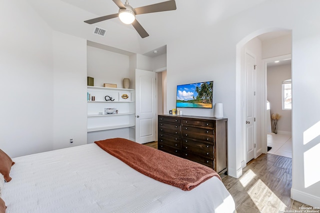 bedroom with visible vents, wood finished floors, baseboards, arched walkways, and a ceiling fan