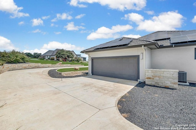 view of side of home featuring a garage, stucco siding, concrete driveway, central air condition unit, and solar panels