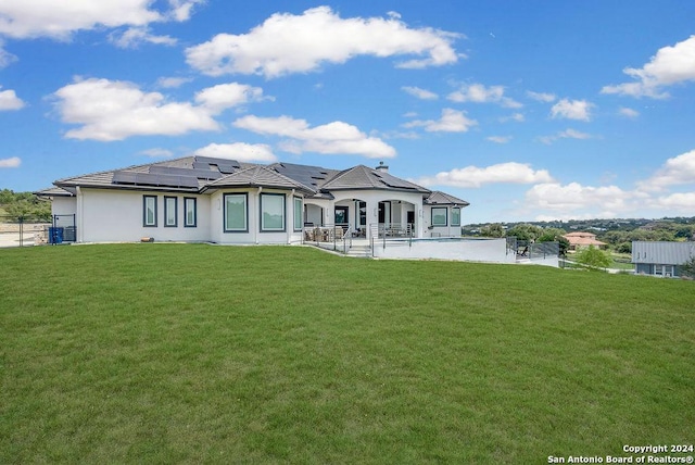 back of property featuring a lawn, solar panels, and a patio area