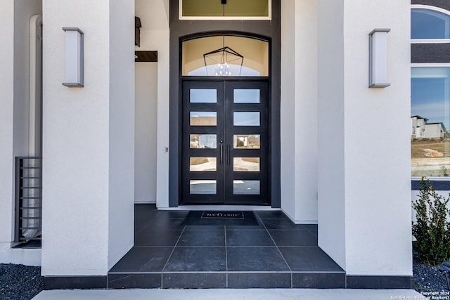 view of exterior entry featuring french doors and stucco siding
