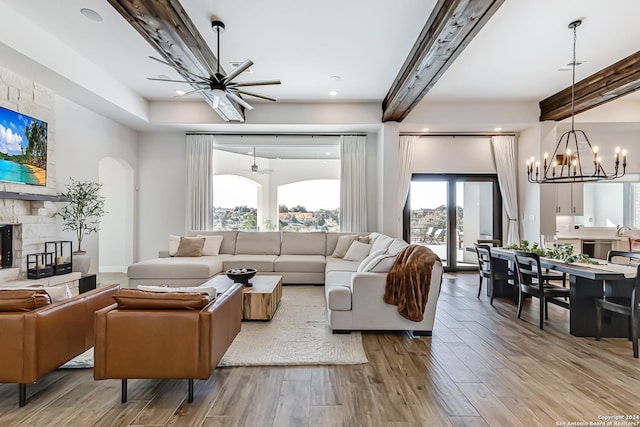 living room with beamed ceiling, arched walkways, a fireplace, and light wood-type flooring