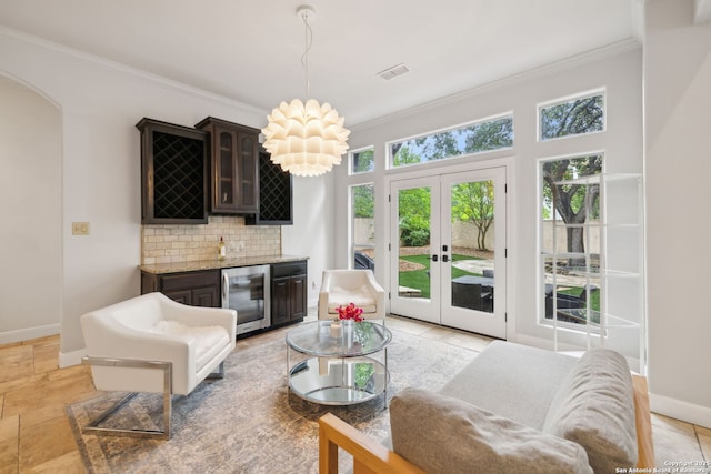 living room featuring wine cooler, french doors, baseboards, ornamental molding, and indoor bar