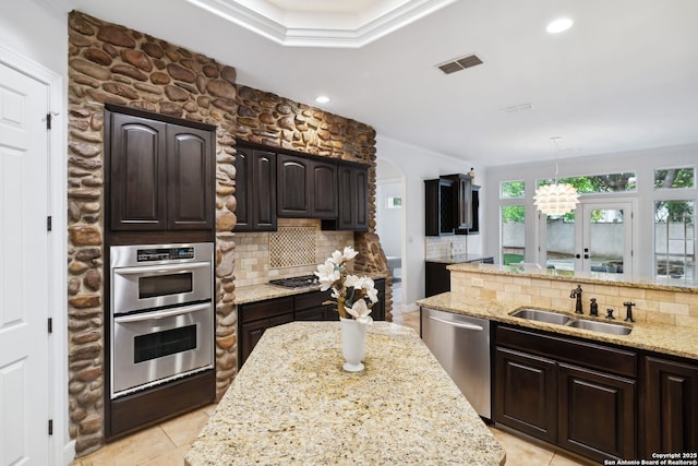 kitchen featuring a sink, appliances with stainless steel finishes, backsplash, light stone counters, and dark brown cabinetry
