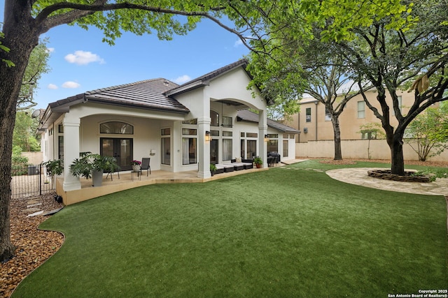 rear view of property featuring a tiled roof, stucco siding, and a patio