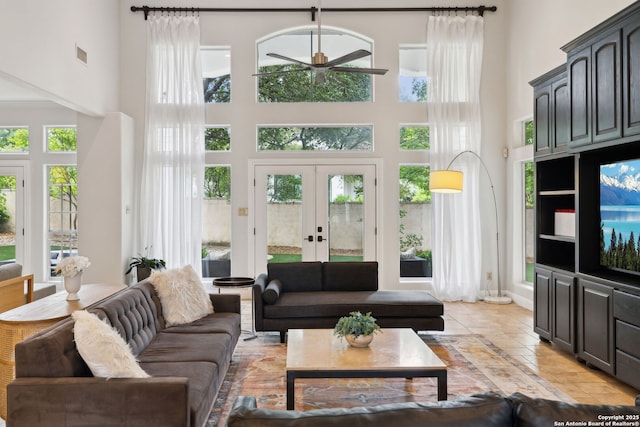 living area with a ceiling fan, french doors, visible vents, and a high ceiling