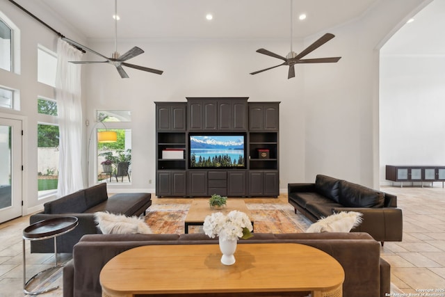 living room with a ceiling fan, a towering ceiling, and recessed lighting